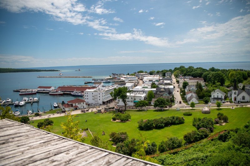 coastline of the bay of mackinac island with white houses green meadow on lake huron